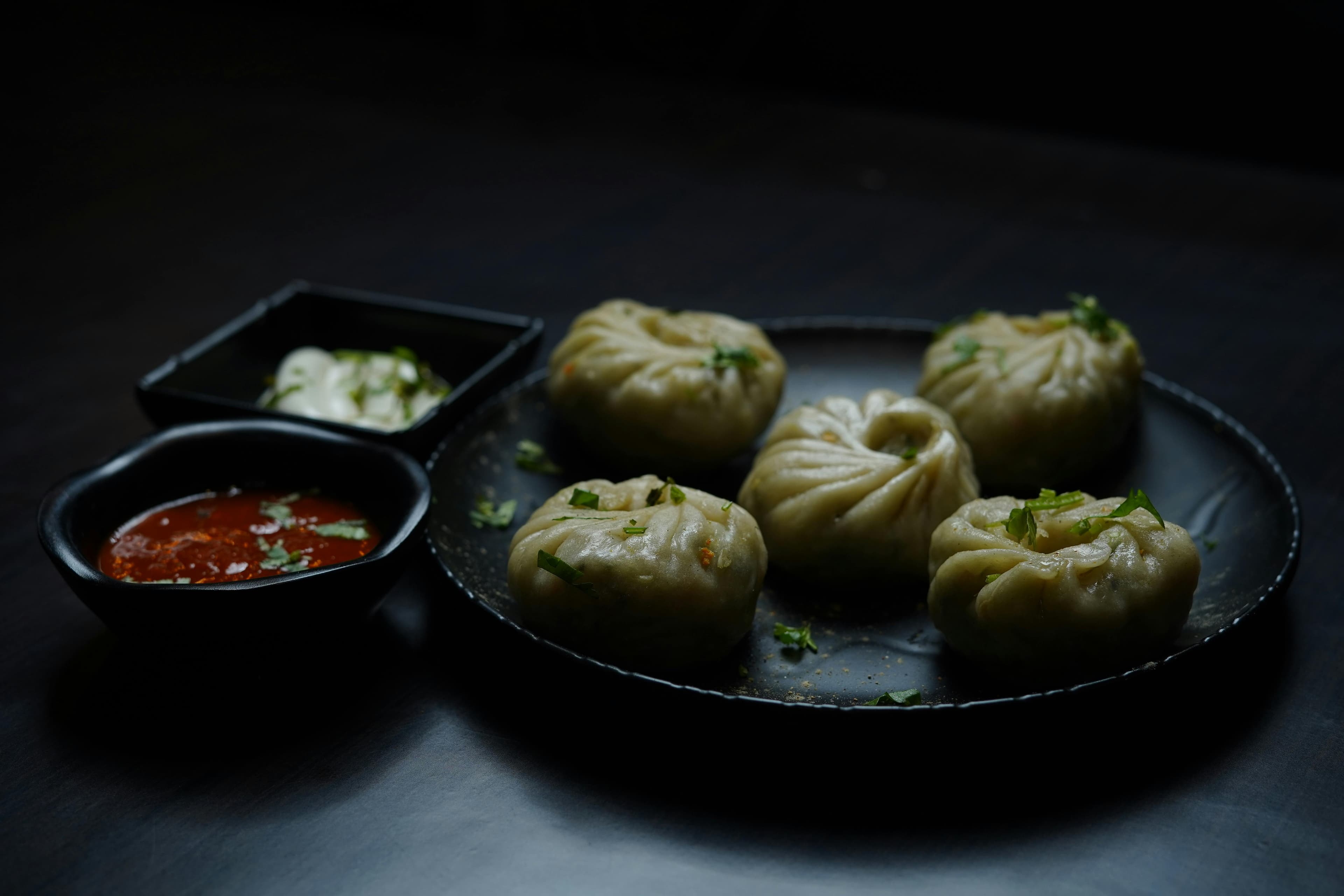 Plate of steaming Kathmandu jhol momo with red sesame chutney on wooden table
